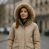 Parka à capuche beige avec fausse fourrure, idéale pour les températures froides en milieu urbain.