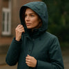 Femme portant une parka imperméable avec capuche sur un fond de pluie. Parka imperméable pour une protection optimale.