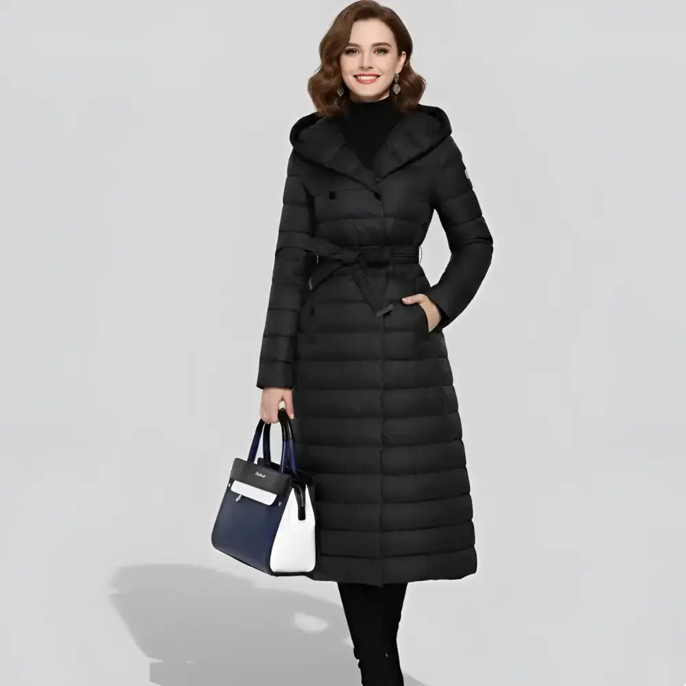 Parka femme longue à capuche noire portée par une femme avec un sac à main.