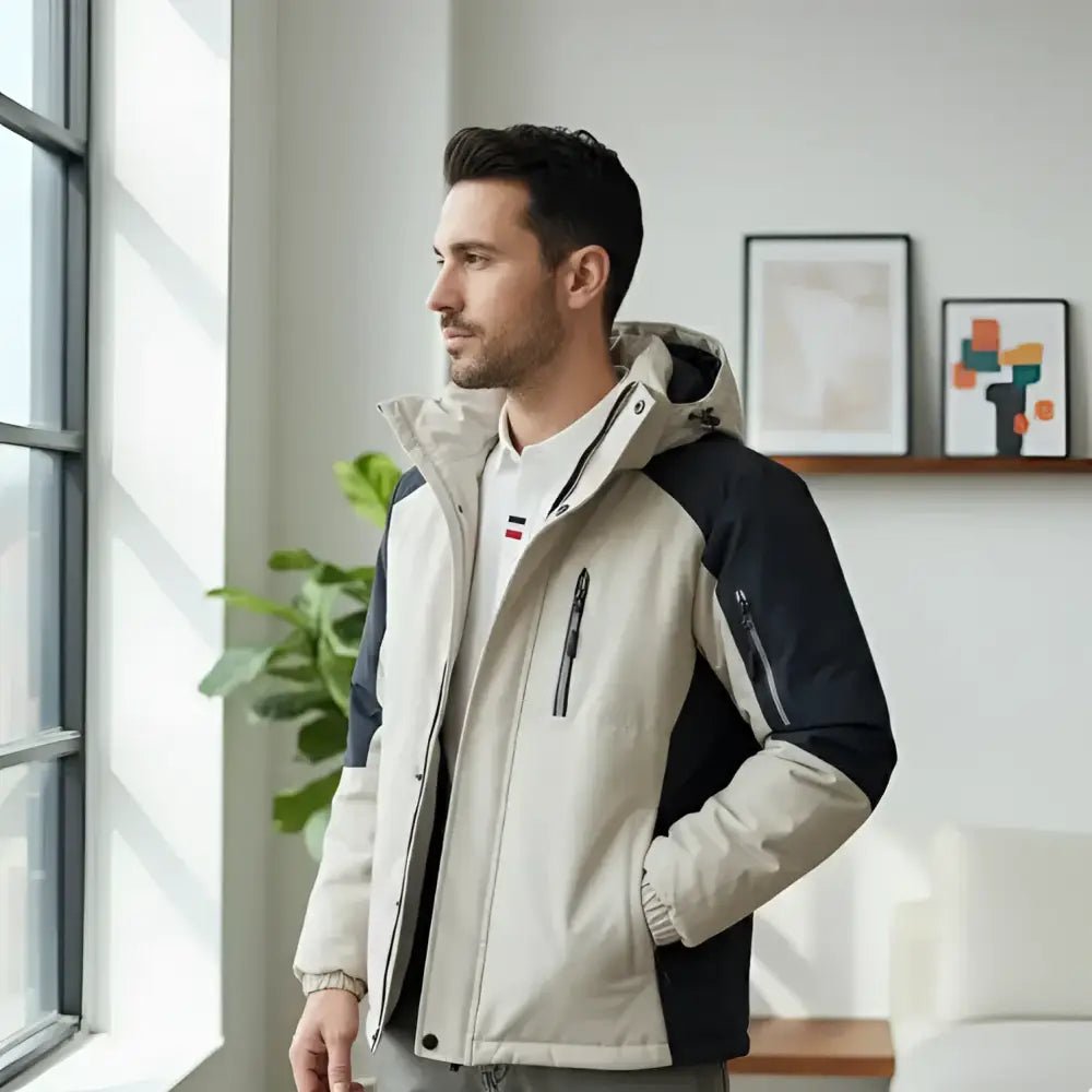 Parka homme bicolore à capuche portée par un modèle dans un intérieur moderne.