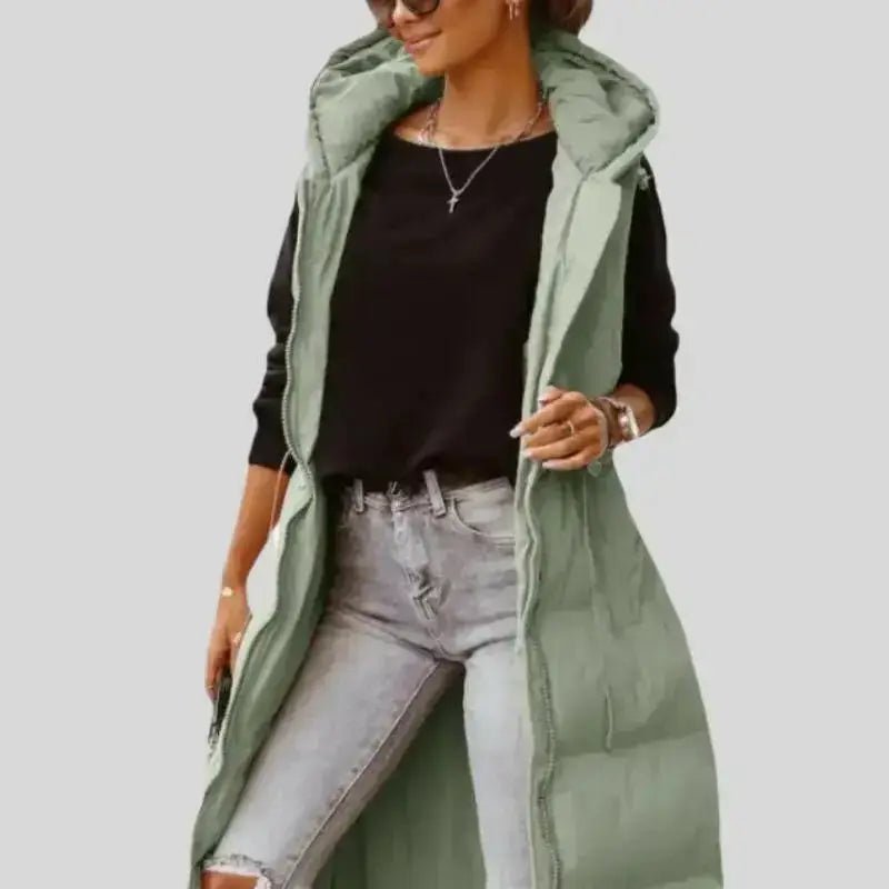 Parka femme sans manches vert militaire matelassée portée avec un haut noir et un jean.