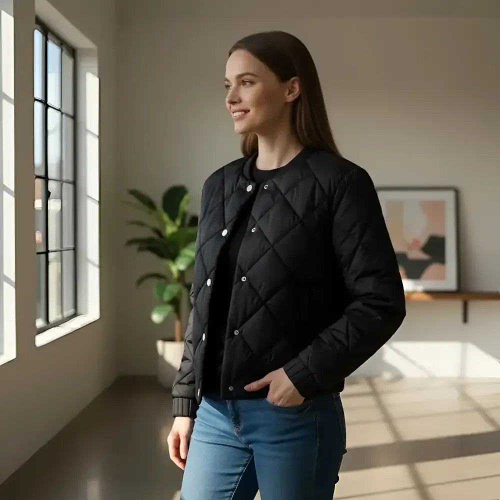 Parka femme courte bombardier noire, style urbain, avec finition matelassée, présentée dans un intérieur lumineux.