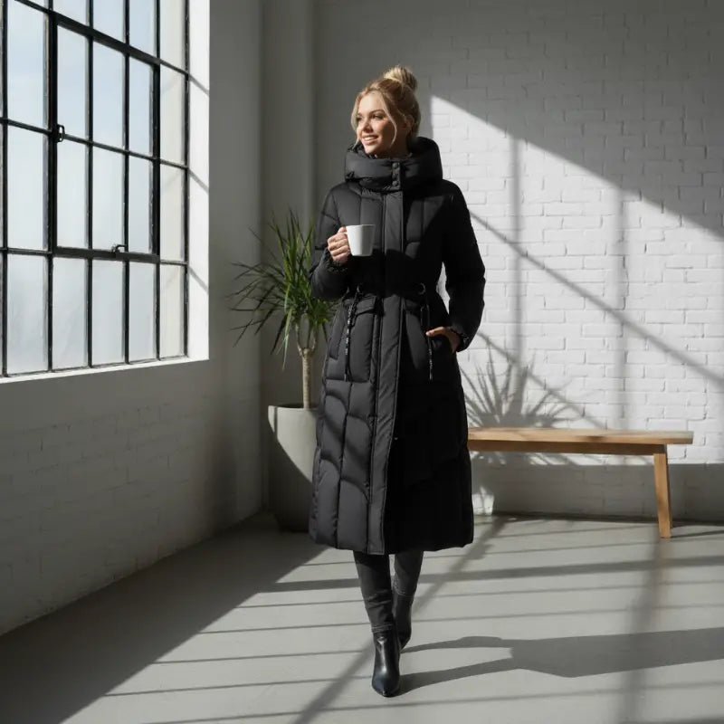Parka noire femme longue La Noctambule avec capuche, tenue élégante et confortable pour l'hiver.