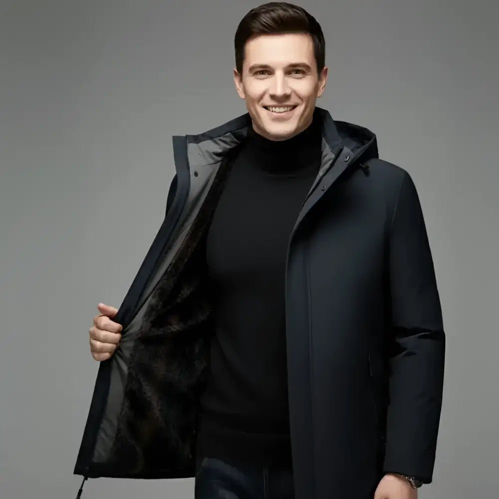 Homme souriant portant une parka homme noire longue à capuche, ouverte, sur fond neutre.