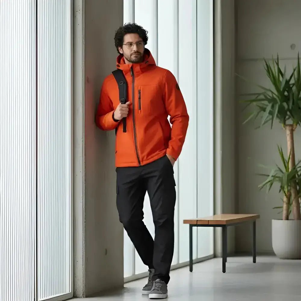 Parka homme bordeaux imperméable à capuche portée par un homme dans un intérieur moderne et lumineux.