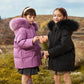 Deux filles en parka fille légère et coupe vent avec hoods en faux fur, tenant des tulipes roses