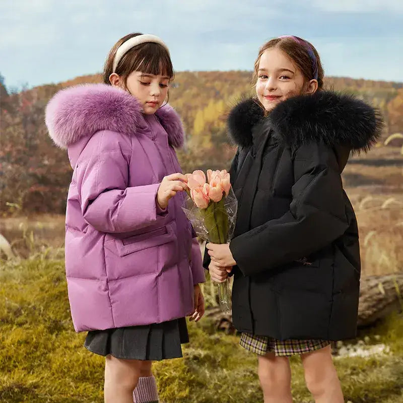 Deux filles en parka fille légère et coupe vent avec hoods en faux fur, tenant des tulipes roses