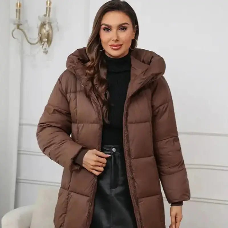 Parka femme noire longue matelassée portée par une femme devant un décor élégant.