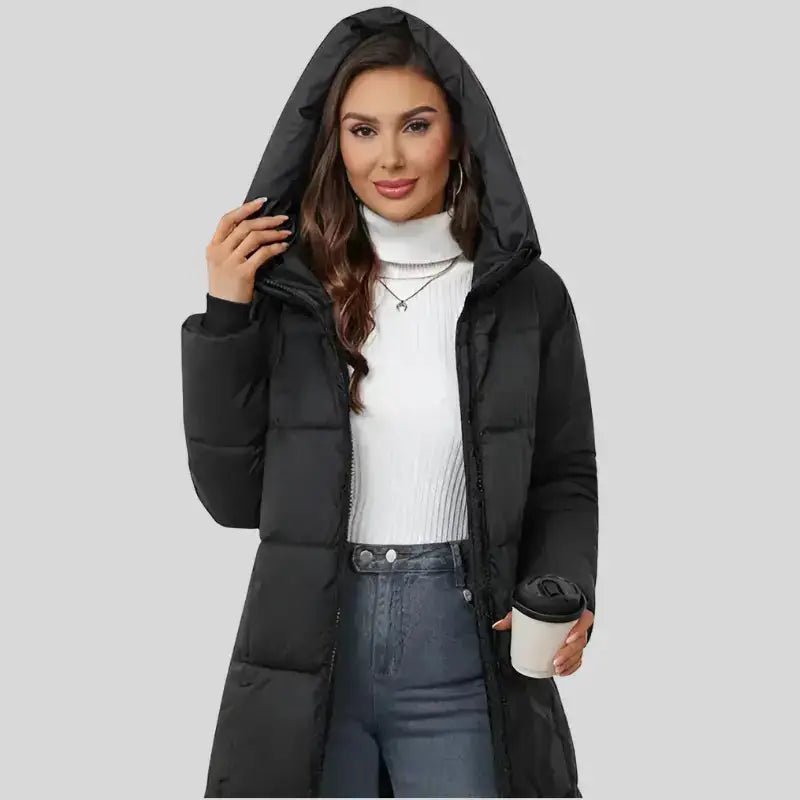 Parka femme noire longue matelassée portée avec un pull blanc et une tasse, idéale pour les journées froides.