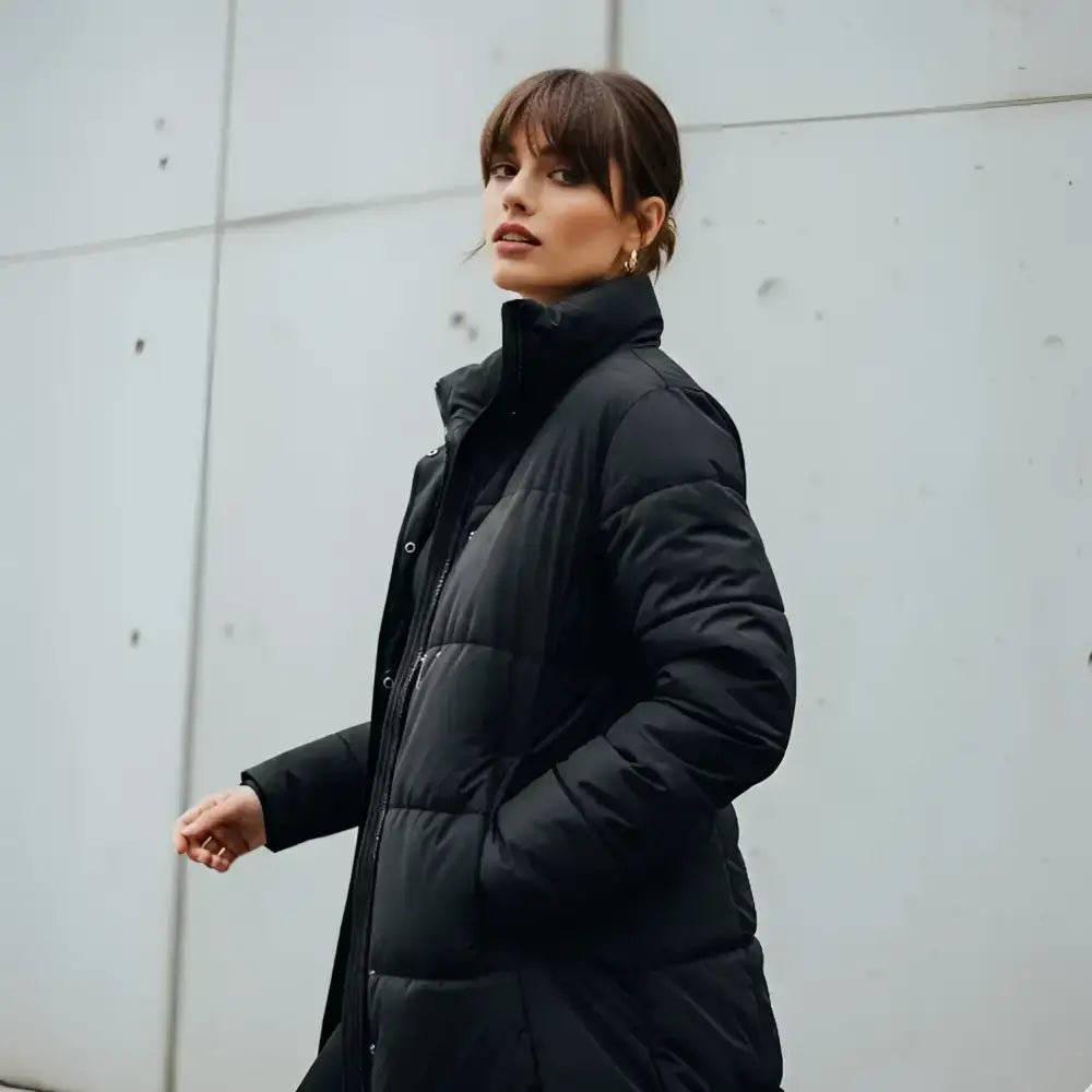 Parka femme longue matelassée colorée à capuche noire portée par une femme dans un environnement urbain.